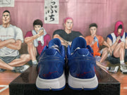 Rear view of the blue sneakers showing heel details, red signature-style markings, and white midsoles
