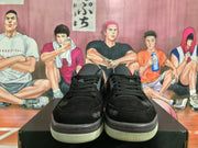 Front view of black low-top sneakers with black laces, textured toe panels, red accents, and light-colored outsoles.