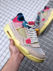 Angled front-side view of the sneaker with cream panels, pink collar, blue accents, and yellow sole.