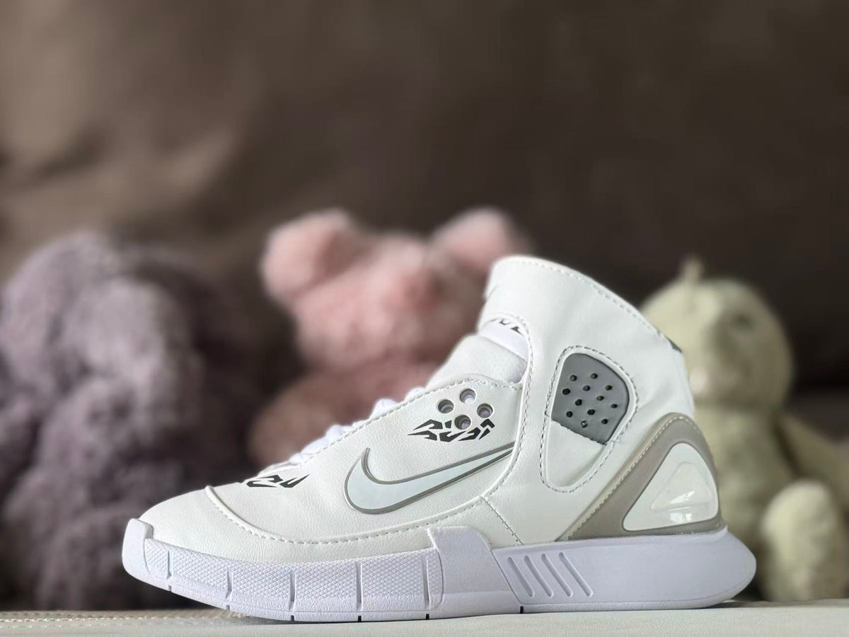 Side view of a white high-top kids’ sneaker with gray accents, ankle strap, perforated panel, and graphic detailing.
