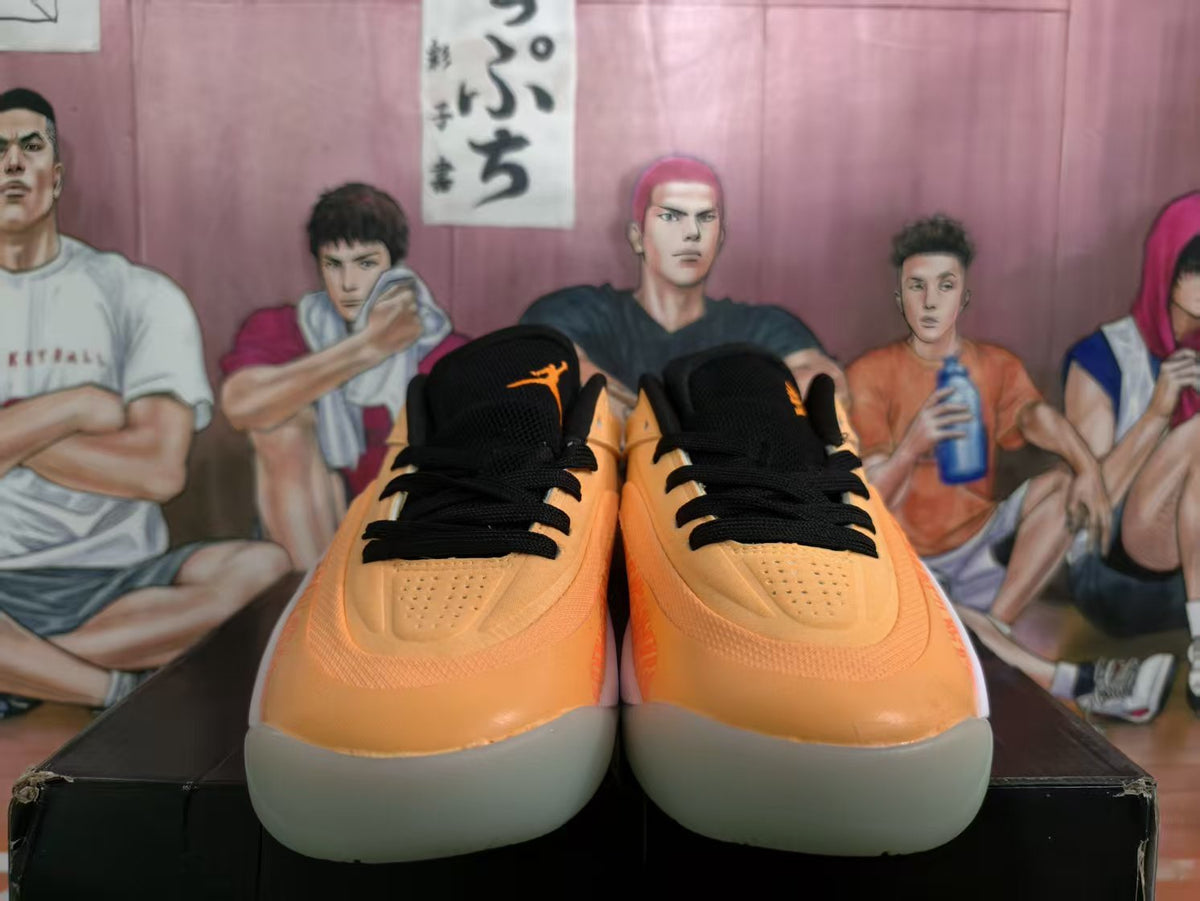 Pair of orange Jordan basketball sneakers shown from the front with black laces and light gray soles.