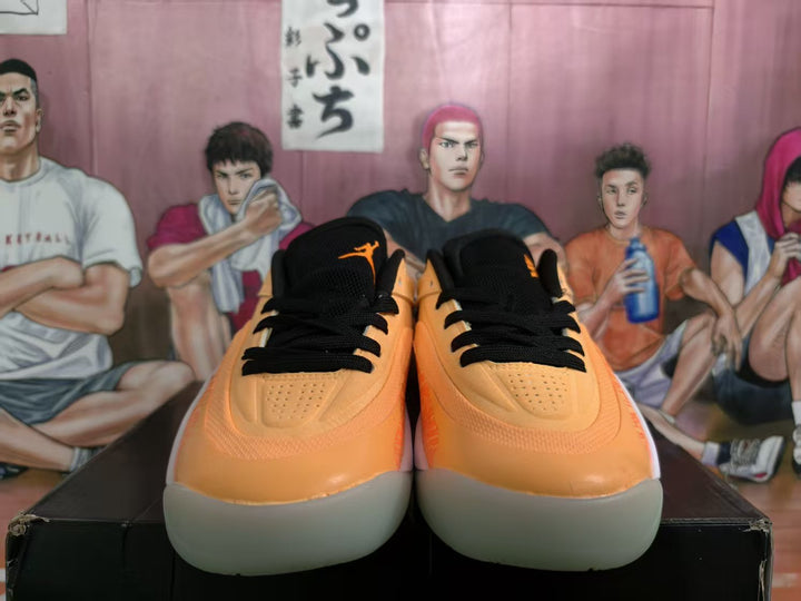Pair of orange Jordan basketball sneakers shown from the front with black laces and light gray soles.