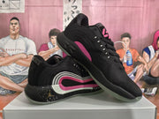 Angled view showing the black sneaker pair, pink side detailing, Jumpman logo, and layered midsole design.