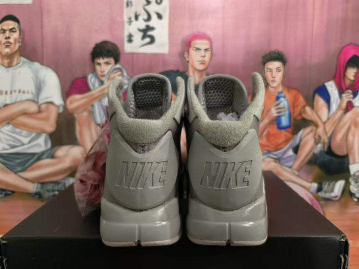 Rear view of gray Nike high-top basketball sneakers showing padded collars, heel branding, and a black shoebox.
