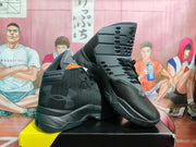 Angled view of the black and silver sneakers, showing the side profile, layered sole construction, ankle vents, and outsole pattern.