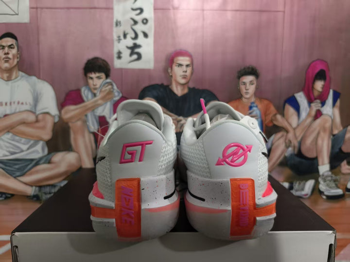 Rear view of white Nike basketball shoes with pink and orange heel accents and GT lettering.