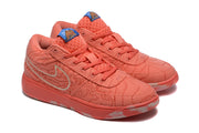 Angled view of the coral sneaker pair showing tonal laces, patterned textile uppers, blue tongue labels, and textured rubber outsoles.