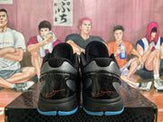 Rear view of the sneakers showing metallic gray heel panels, glossy black heel sections, red script details, and blue outsole edges.