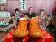 Front view of the orange sneakers showing tonal laces, textured uppers, and rounded toes.
