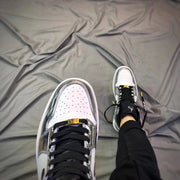 Close-up view of the white toe box, silver trim, black laces, and gold-toned lace detail.