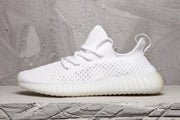 Side profile of a white sneaker showing the textured upper, heel pull tab, and ribbed sole unit.