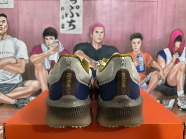 Rear view of Nike running shoes in brown, gray, cream, and navy with visible heel branding.