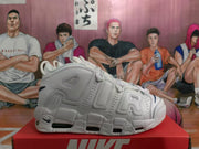 Side profile of a white Nike sneaker showing layered panels, perforations, oversized AIR lettering and segmented sole cushioning.