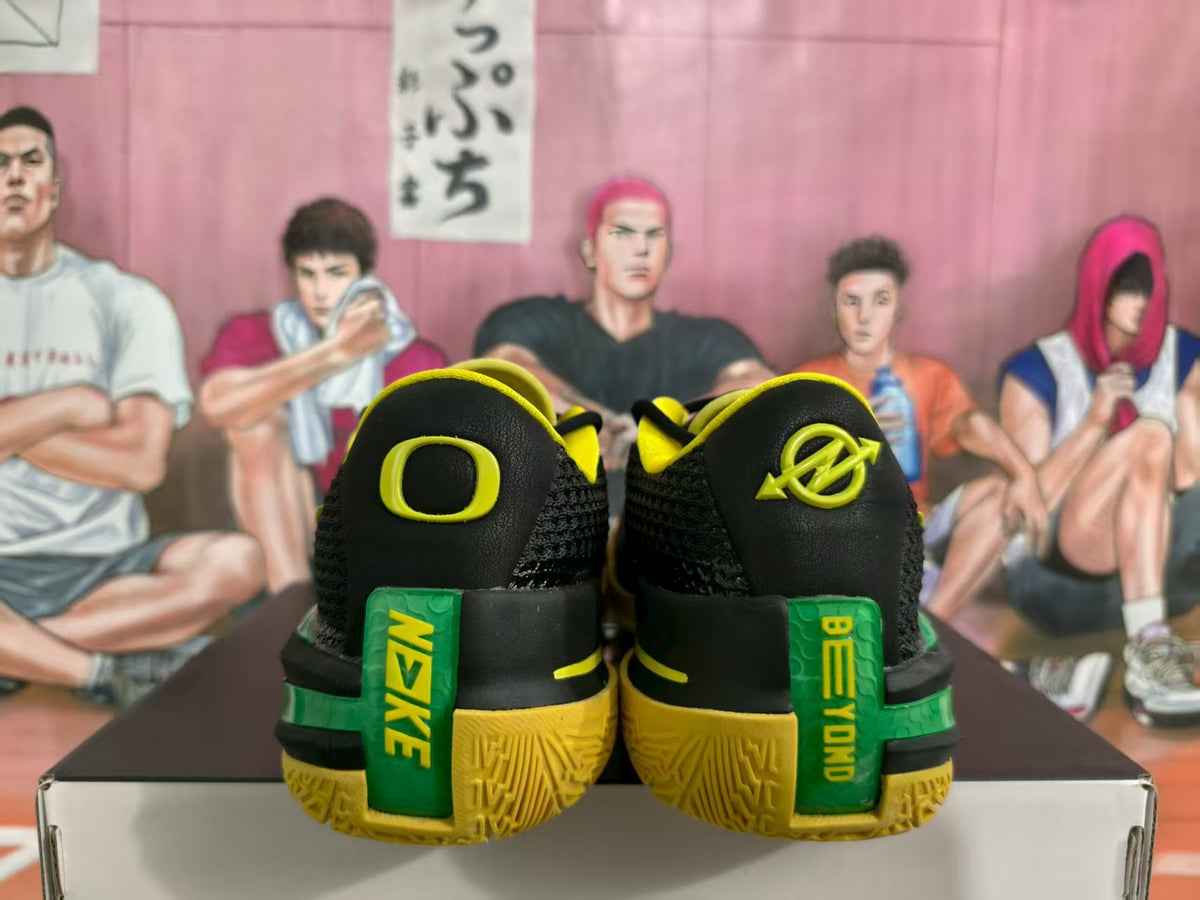 Rear view of black basketball sneakers with yellow and green accents, displayed on a shoe box.
