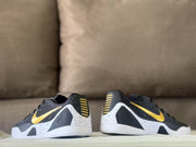 Rear view of the sneakers showing black heel sections, gold heel accents, and white midsoles.