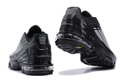 Rear and outsole views of black and grey Nike Air Max Plus sneakers.
