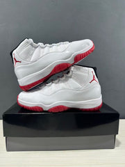 Pair of white and red Jordan Air Jordan 11 Retro Low sneakers displayed on a black shoebox.