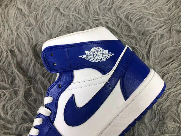 Close-up of the white and blue mid-top sneaker showing the collar branding, blue Swoosh, white panels, and white laces.