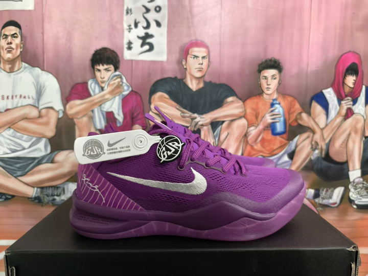 Side view of purple Nike basketball sneakers displayed on a black box, showing the contrasting Swoosh and patterned heel panel.