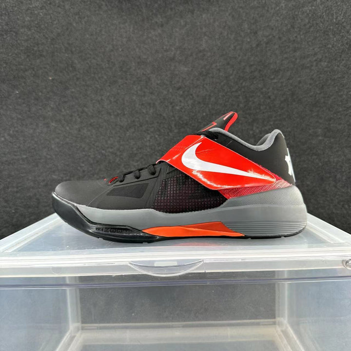 Side view of a black and gray Nike basketball shoe with red accents, a forefoot strap, and a white side logo.