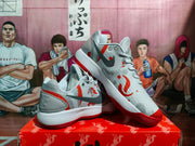 Angled view of the Nike sneakers showing the perforated side panels, dark Swoosh, red accents, and layered outsole.