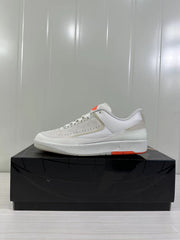 Side profile of the low-top sneaker showing the light beige upper, white midsole, and orange outsole accent.