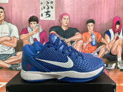 Side view of a blue Nike basketball sneaker showing the white swoosh, textured upper, red number 8 and layered white midsole.