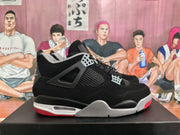 Side view of a black sneaker showing mesh panels, grey lace wings, a visible air unit window, and red outsole details.
