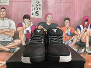 Front view of black basketball sneakers showing the Kobe logo on the tongues, patterned laces, and white-gray midsoles.