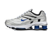 Side view of a silver Nike Shox Ride 2 sneaker with blue accents and visible cushioning columns.