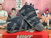 Angled view of a pair of navy and gray Nike high-top sneakers displayed on a Nike box.