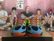 Front view showing the blue toe, black mesh panels, and orange laces.