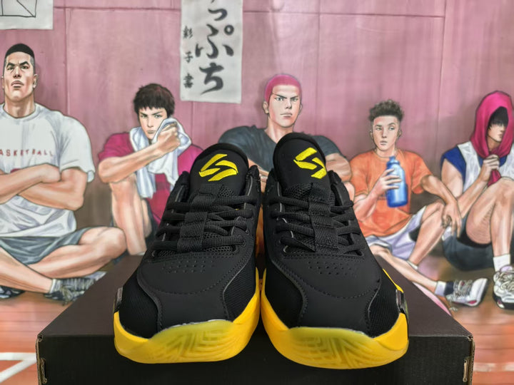 Front view of black and yellow Jordan basketball sneakers displayed on a box.