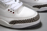 Close-up of the white textured upper, white laces, stitching, and elephant-print toe overlay.