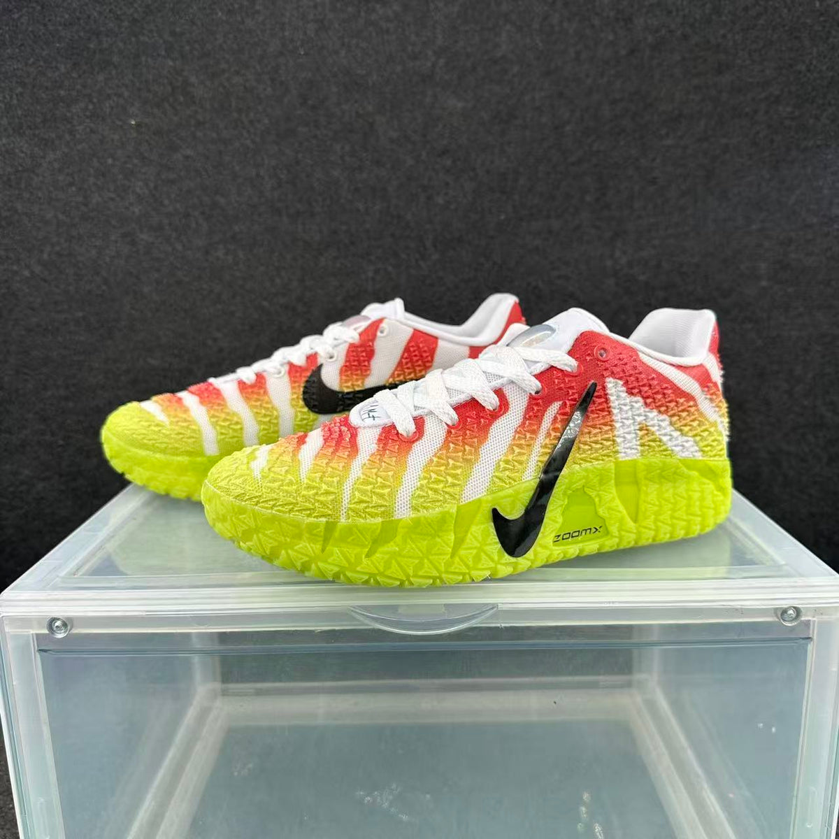 Pair of Nike sneakers with red, white, yellow, and neon yellow panels, black Swoosh branding, and ZoomX lettering.