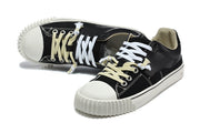 Black low-top sneakers with white and cream-colored laces, shown from above.