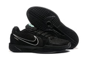 Black sneakers displayed with one outsole facing upward, showing the textured traction pattern and side branding.