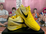 Angled view of yellow Nike basketball sneakers showing black Swoosh branding, yellow laces and speckled midsole detailing.