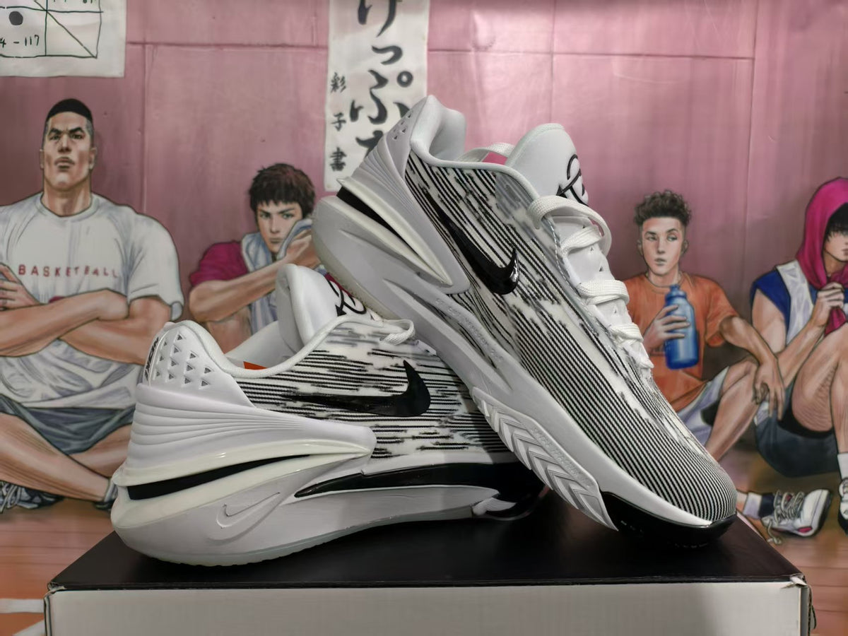 Pair of white and black Nike sneakers displayed on a shoebox, showing the side profile and splatter-like upper pattern.