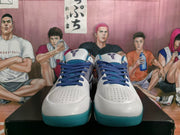 Front view of white basketball sneakers with dark blue laces, blue tongue logos, perforated toe panels, and teal outsoles.