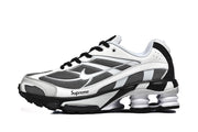 Side view of white, black, and gray Nike Shox Ride 2 sneakers with mesh panels, a sculpted sole, and Supreme branding.