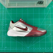 Side profile of the sneaker placed on a green measurement mat, showing the silver upper, wine-red overlays, and white midsole.