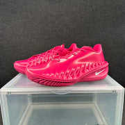 Three-quarter view of a pair of bright pink low-cut basketball sneakers with lace fastening and textured soles.