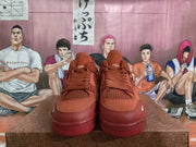 Front view of red low-top sneakers showing the lace-up construction, padded tongues, woven panels, and side marks.