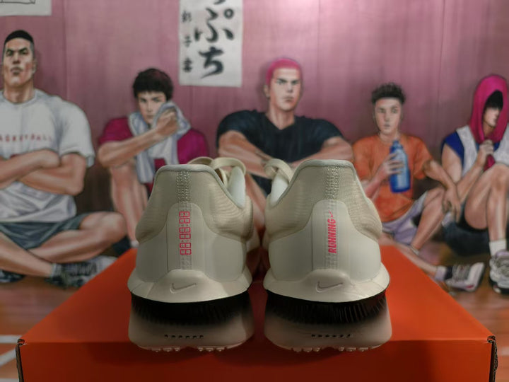 Rear view of beige and black Nike running shoes showing heel branding, black outsole sections, and a red shoe box.
