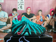 Side view of a teal Nike basketball sneaker with black patterned detailing, teal laces, a red-and-white Swoosh and a visible “ZoomX” marking.