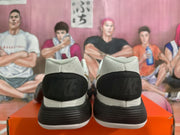 Rear view of the white sneakers showing black heel panels, black midsoles, and white outsole edges.