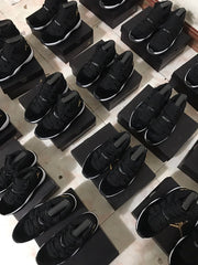 Overhead view of several pairs of black high-top sneakers arranged on shoeboxes.