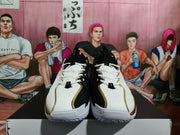 Front view of a pair of white, black, and gold Nike basketball sneakers displayed on a box.