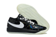 Side view of a black sneaker with white side branding, glossy patterned panels, and a translucent outsole.